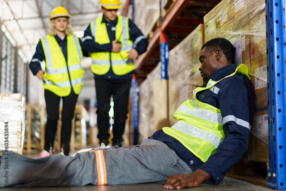 Male warehouse worker have an accident during working in the storage warehouse and his friends come to help or assist him and taking him to the safety area. Male warehouse worker have an accident during working in the storage warehouse and his friends come to help or assist him and taking him to the safety area.