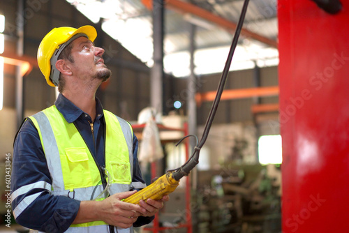 Factory worker - technician controlling a heavy crane in factory close up at his hands holing a crane controller.