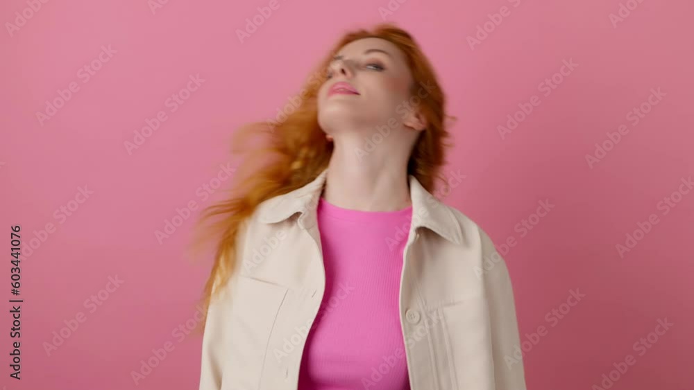 Excited redhead woman dancing moving head and waving her curly hair, having fun , enjoying life, entertainment. Smiling happy emotional female lady dance. Indoor studio isolated on pink background. Excited redhead woman dancing moving head and waving her curly hair, having fun , enjoying life, entertainment. Smiling happy emotional female lady dance. Indoor studio isolated on pink background.