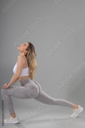 Fitness woman doing lunges exercises for leg muscle workout training in studio with grey background.the girl looks naturally beautiful, attractive and sexy.natural beautiful sexy girl doing exercises