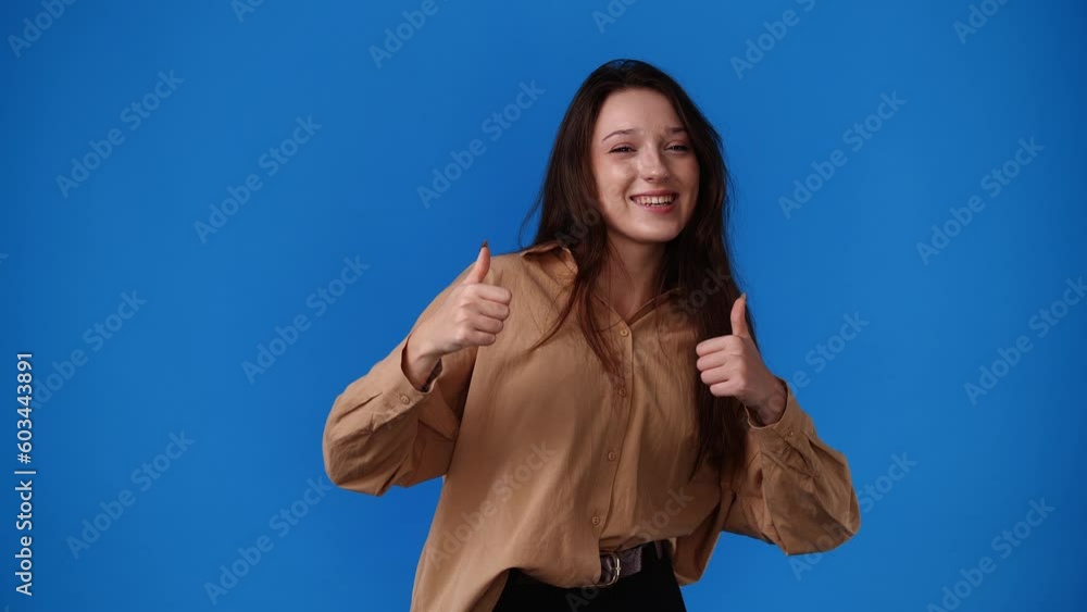 4k video of girl showing thumbs up and smiling over blue background. 4k video of girl showing thumbs up and smiling over blue background.
