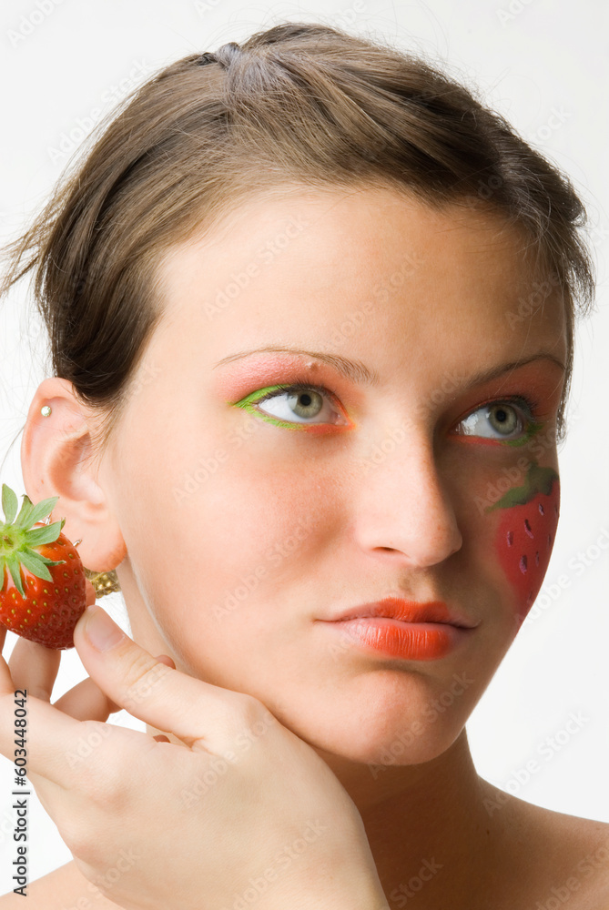 portrait of a young and cute brunette with big strawberry painted on her face and colored eyes portrait of a young and cute brunette with big strawberry painted on her face and colored eyes