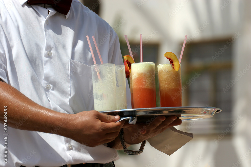 Waiter handling a salver with colorful cocktails.
