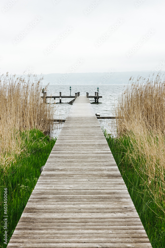 Fototapeta premium Serene wooden landing stage on a cloudy day at the Ammersee Lake in Bavaria, southern Germany