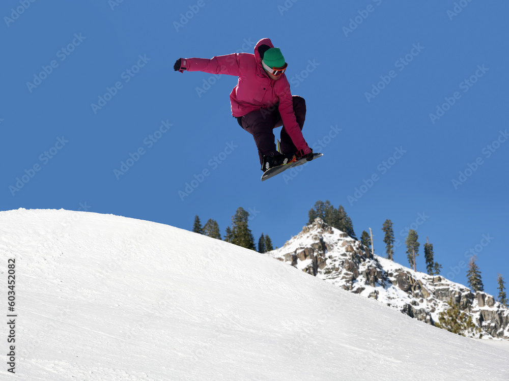Teenager jumping high on a snowboard at the ski resort