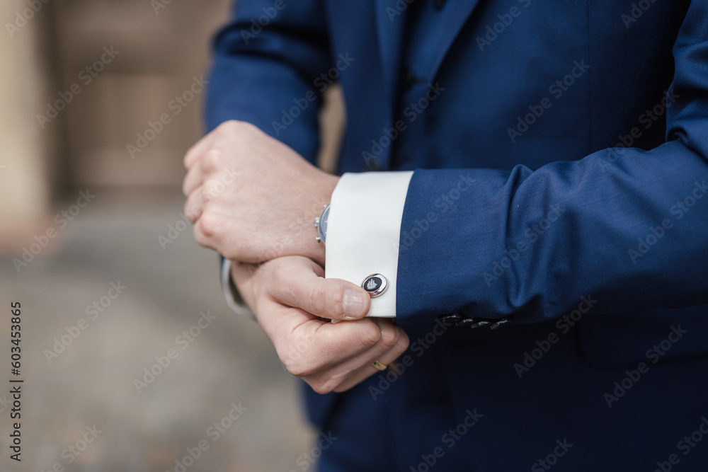 Groom showing cufflinks at his wedding day close-up