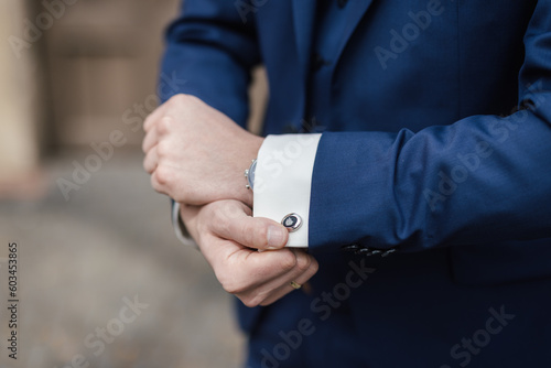 Groom showing cufflinks at his wedding day close-up