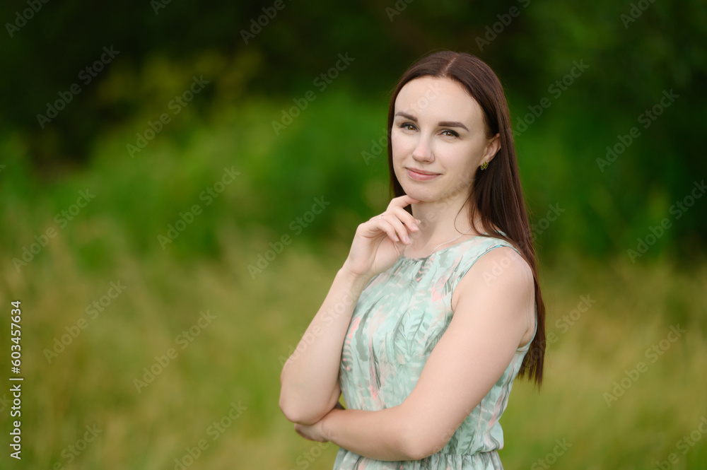Summer portrait of a happy pensive woman in a city park. The concept of lifestyle, travel, vacation, unity with nature Summer portrait of a happy pensive woman in a city park. The concept of lifestyle, travel, vacation, unity with nature