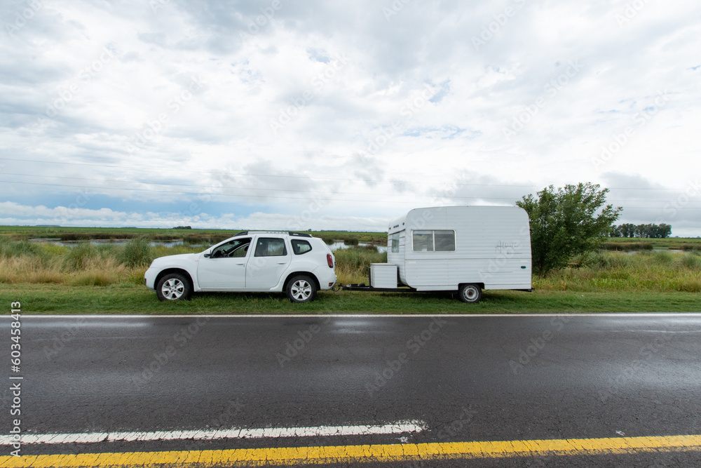 Car transporting a trailer on the side of the road, no people, country scenery