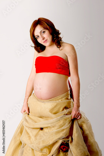 Pregnant woman posing on white with beautiful dress
