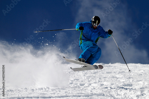 Skier jumping on a slope against blue sky.