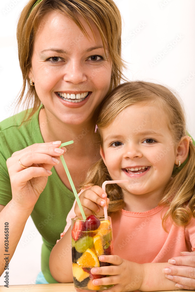 Happy woman and little girl drinking a fruity refreshment with straw Happy woman and little girl drinking a fruity refreshment with straw