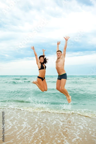 Happy young couple jumping in the sea