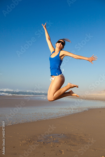 Beautiful young woman jumping on the beach