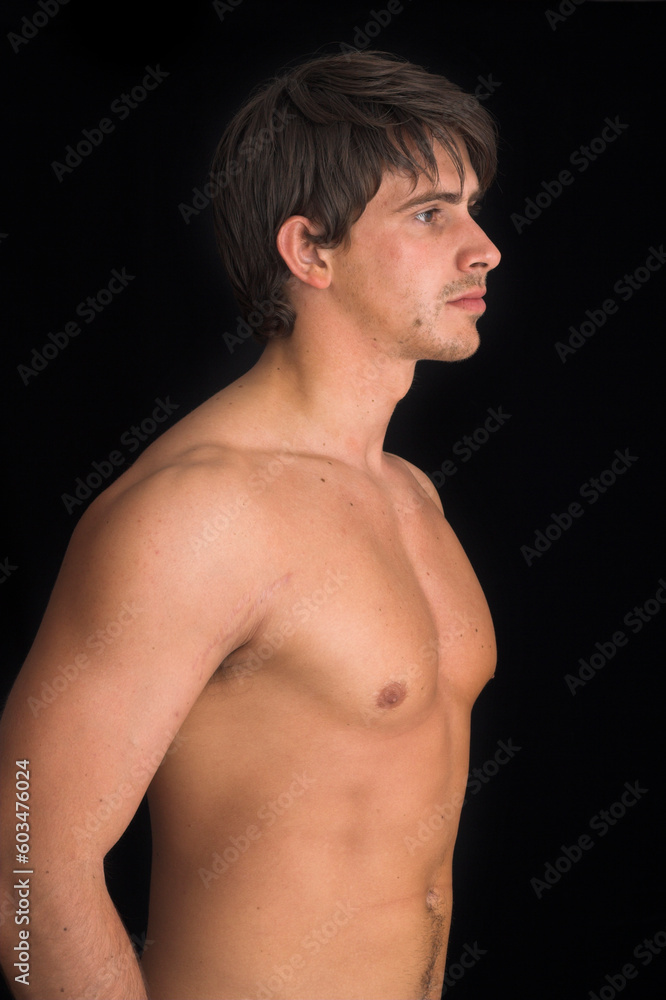 portrait of young man standing with no shirt on over black background portrait of young man standing with no shirt on over black background