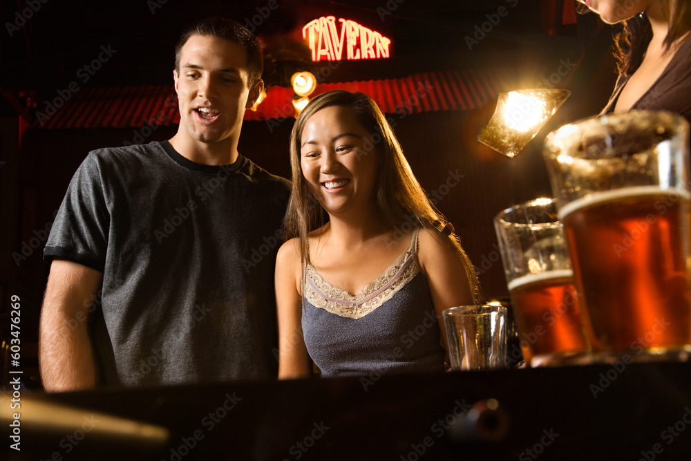 Young couple teamed up at foosball game in pub. Young couple teamed up at foosball game in pub.