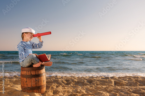 Valokuvatapetti Happy child sitting on old barrel against sea and sky
