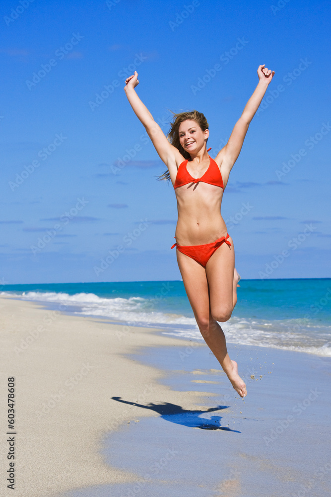 Beautiful Caucasian female teenage having fun on South Beach jumping into the air wearing a swimsuit Beautiful Caucasian female teenage having fun on South Beach jumping into the air wearing a swimsuit
