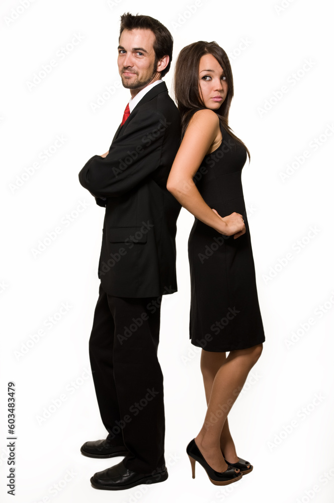 Full body of attractive young brunette man and woman man in black business suit and woman in black dress standing back to back over white Full body of attractive young brunette man and woman man in black business suit and woman in black dress standing back to back over white