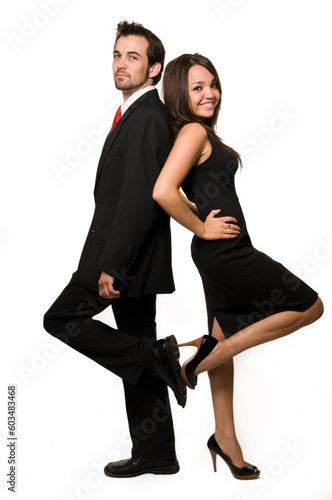 Full body of an attractive brunette woman standing with back up against an attractive man in business suit over white