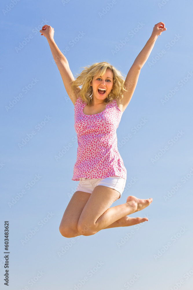 A beautiful young blond woman jumping high in the air with a big smile A beautiful young blond woman jumping high in the air with a big smile