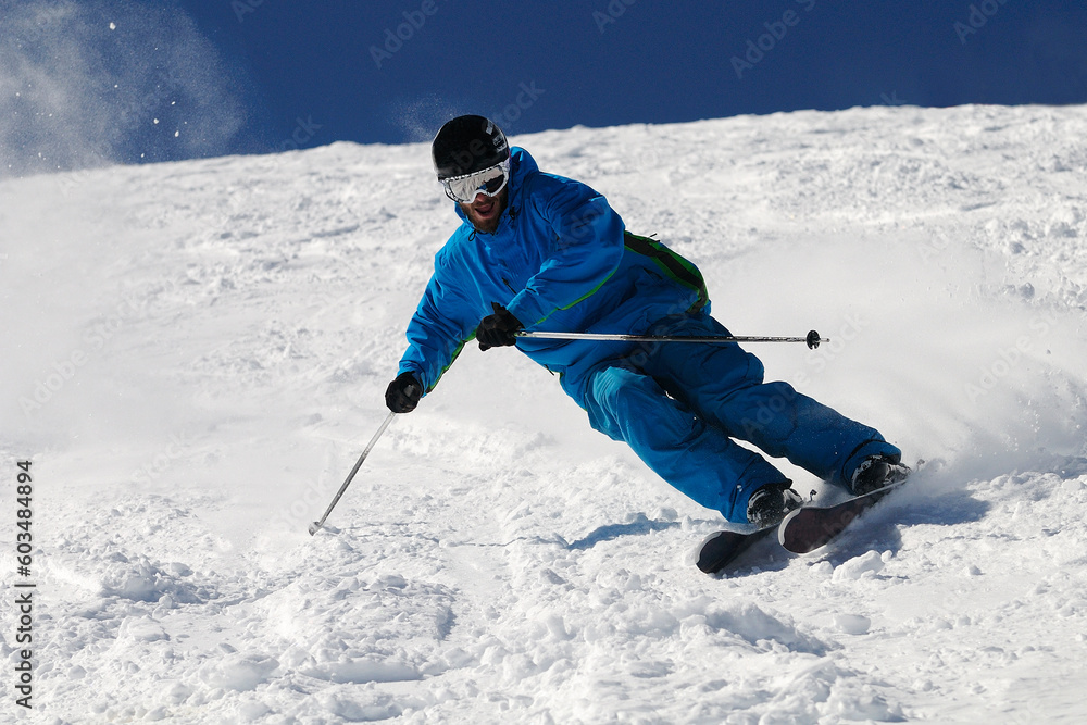 Φωτογραφία Skier moving down on ski slope against blue sky.