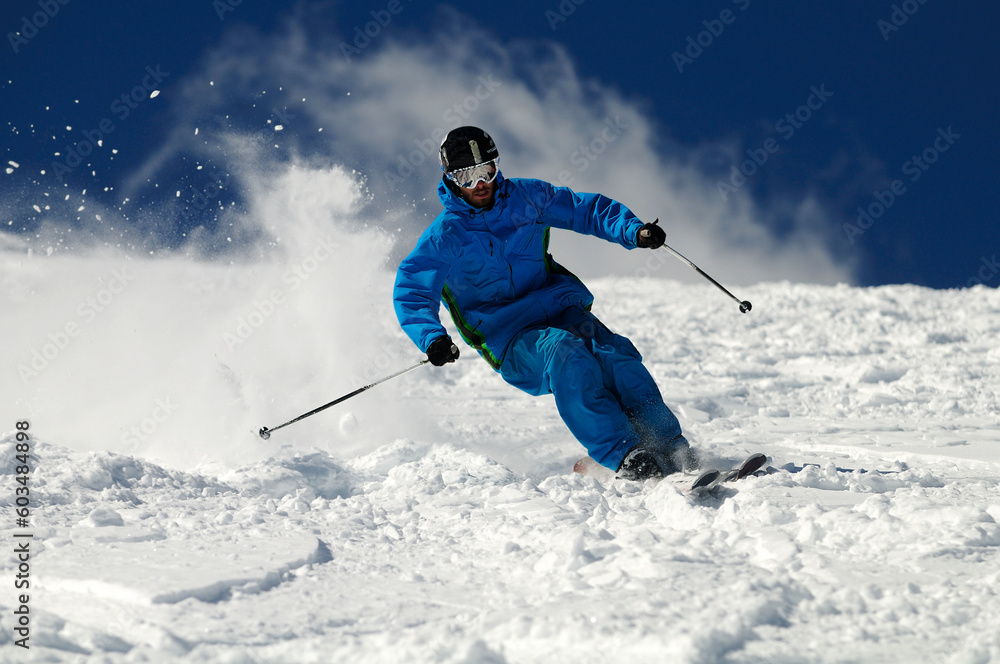 Skier moving down on ski slope against blue sky. Skier moving down on ski slope against blue sky.