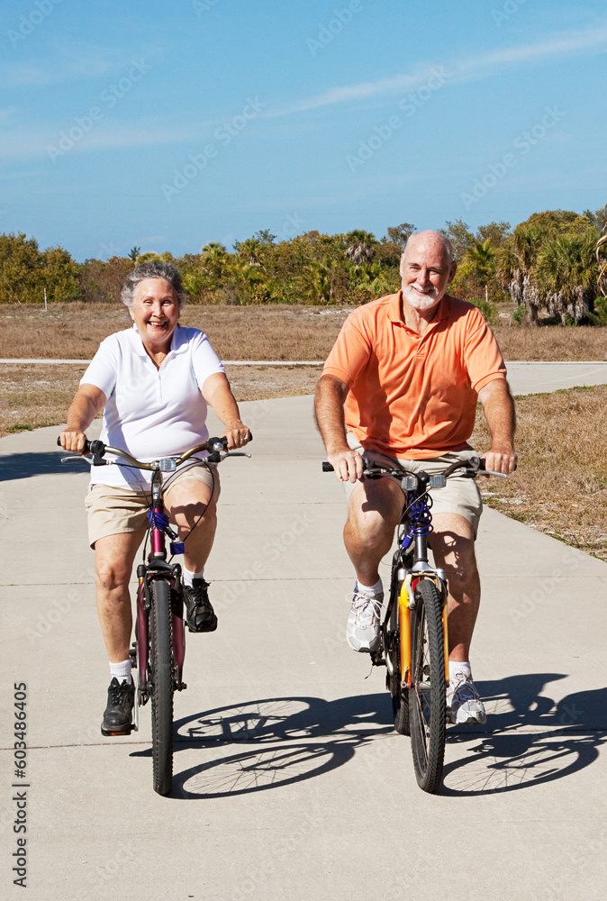 Senior couple has fun riding their bicycles on a tropical vacation.