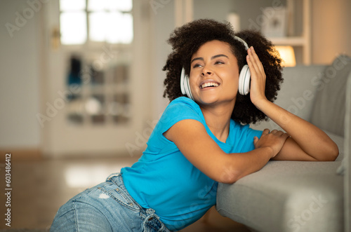 Canvas Print Satisfied happy millennial curly black woman in wireless headphones enjoys free