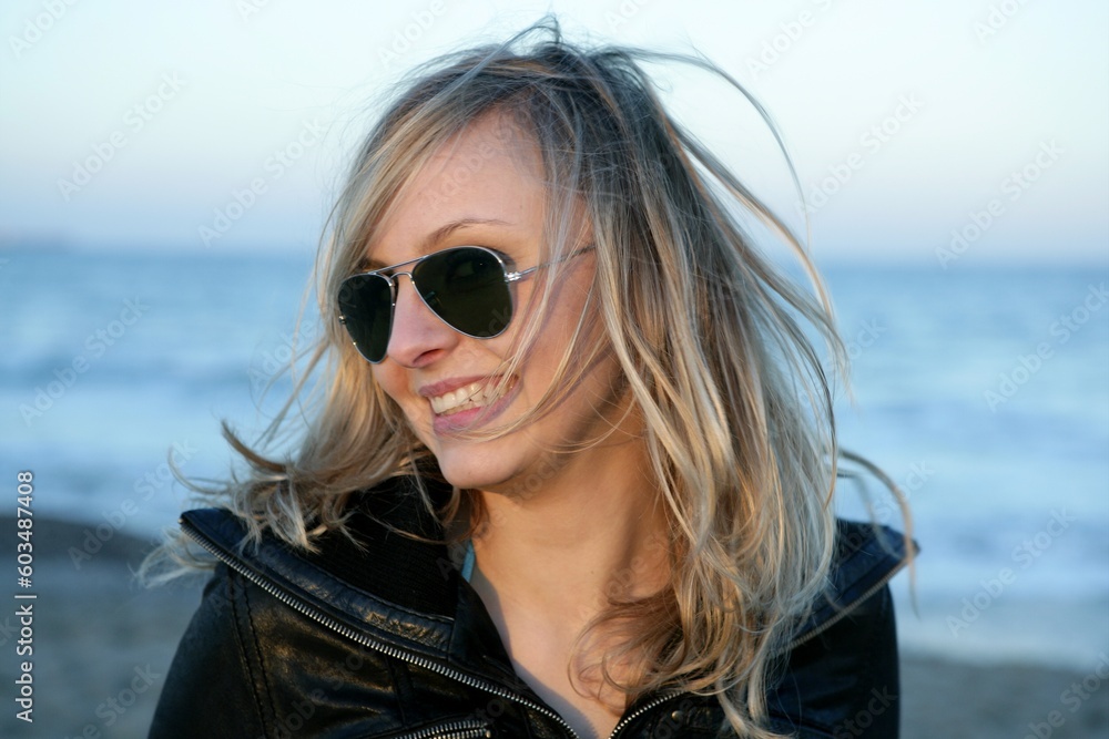 Blond girl with retro sunglasses on the blue beach, wind Blond girl with retro sunglasses on the blue beach, wind