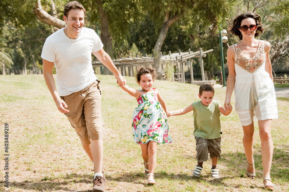 Fototapeta premium Family running with two young children at the park