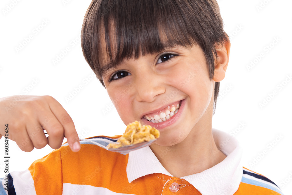 Smiling young boy with spoon of flakes, closeup on isolated white background Smiling young boy with spoon of flakes, closeup on isolated white background