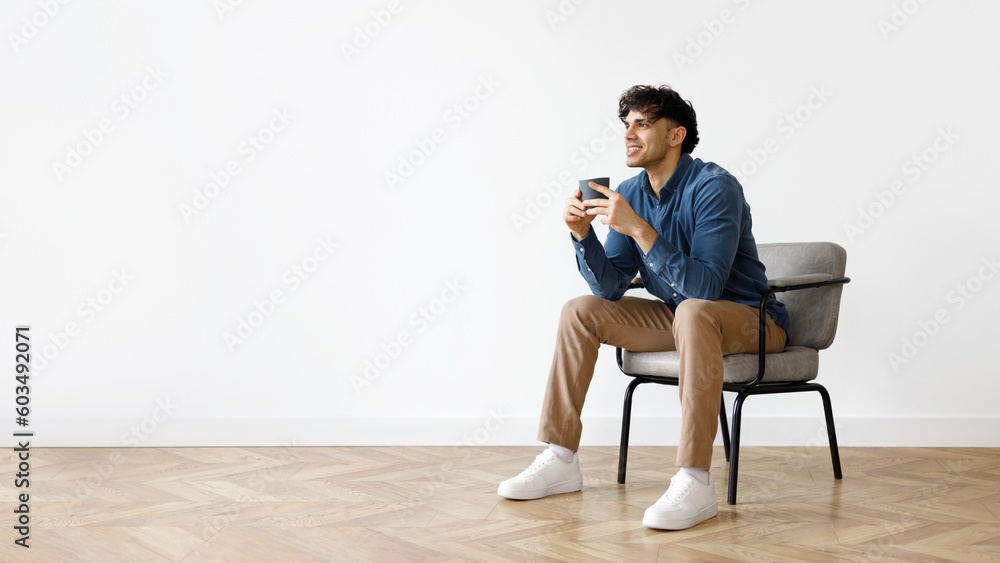 Middle Eastern Man Relaxing In Armchair With Cup Of Coffee