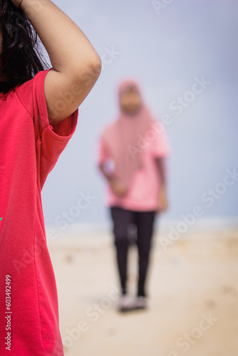 Blurred photo image of a hijab girl in a pink dress by the beach in the evening