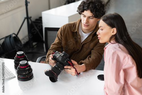 Picture review. Photographer man and yougn female model discussing shots after photoshoot in studio photo