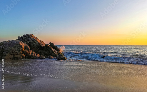 Surfer waves turquoise blue water rocks cliffs boulders Puerto Escondido.