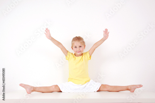 Cute little girl making splits on white background