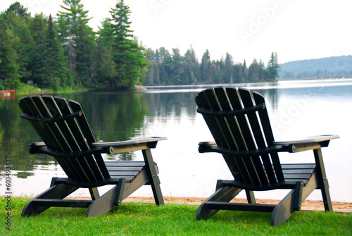 Two wooden chairs on a lake shore in the evening