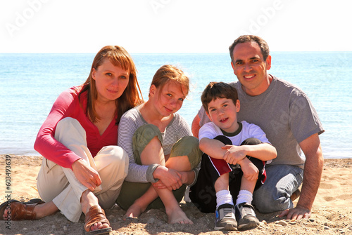 Portrait of a happy family of four sitting on a sandy beach