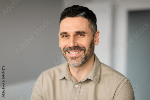 Portrait of happy middle aged businessman working in office, posing and smiling at camera, copy space