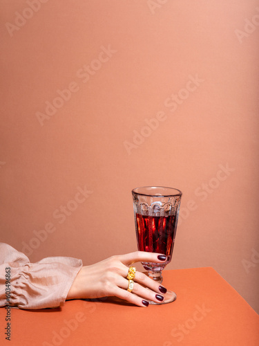 Unrecognisable person in luxury beige silk shirt with well cared hands and manicured nails holding glass of wine. Concept of Wine shop, wine tasting, bar, wine list.