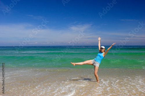 Beautiful happy woman spreading water on the beach