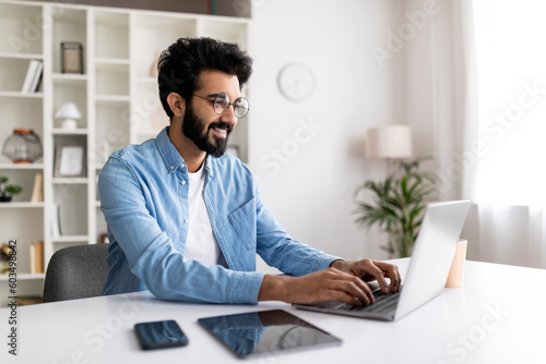 Millennial indian freelancer guy working online on laptop at home office