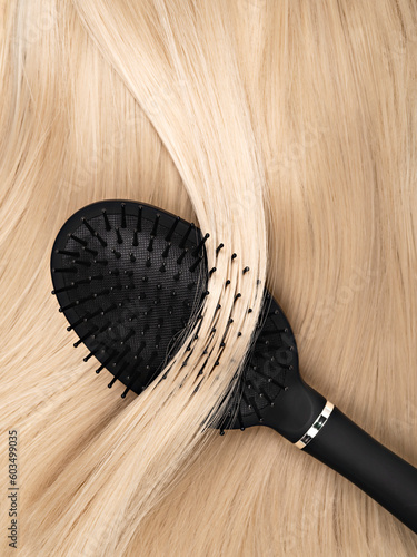 Close up of shiny long blonde straight hair with healthy structure and hairbrush. Process of salon treatment, daily hair care routine. Hair styling concept. Background for hairdresser business.