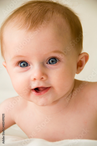 Cute baby girl playing on a bed with a white background