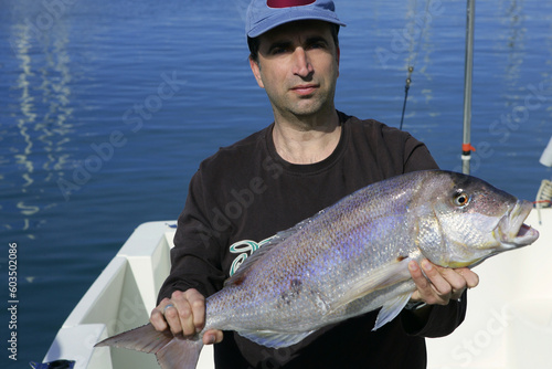 Fisherman showing proud his good catched saltwater fish, over boat