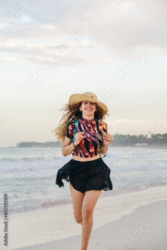 young girl with hat on the beach running