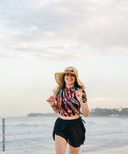 young girl with hat on the beach running