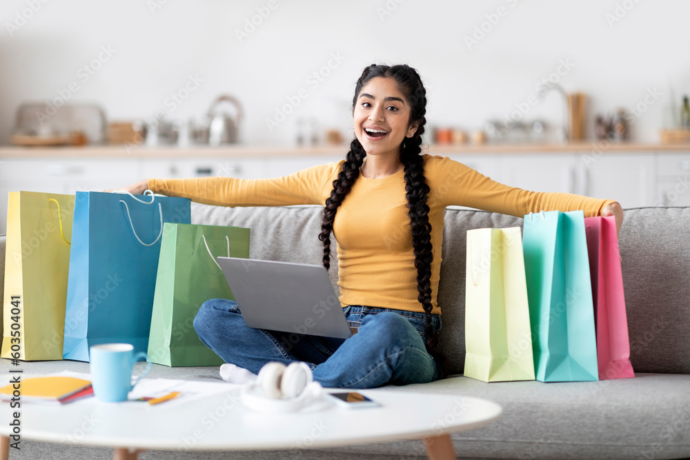 Big Sales. Happy Woman With Laptop Sitting Among Shopping Bags At Home