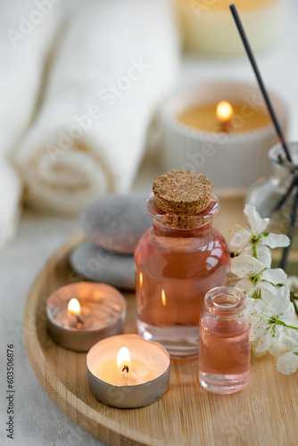 Aromatherapy  home decor concept. Glass perfume bottle  elegant composition with spring flowers. Burning candles  spa setting  essential oils  organic pure aromatic ingredients  atmosphere of relax
